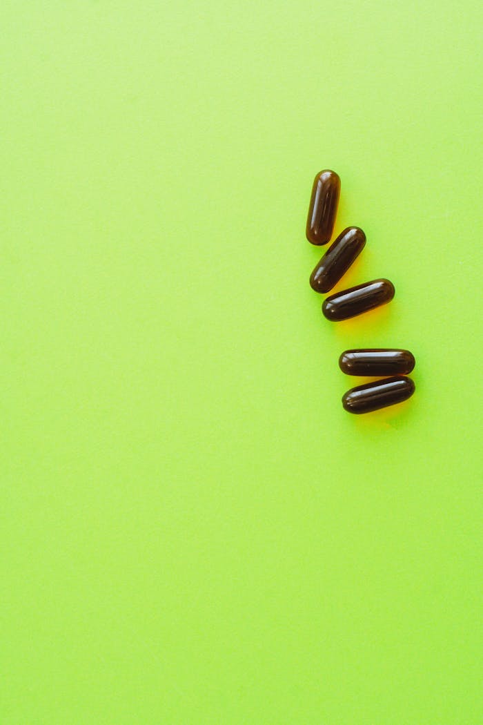 Minimalist photo of dark capsules on a vivid green background, ideal for health themes.